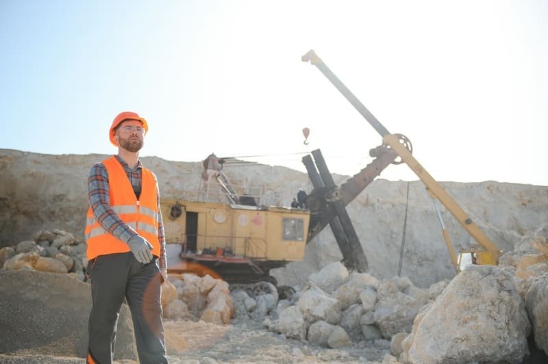 A construction site with a DTH drilling machine and workers in safety gear