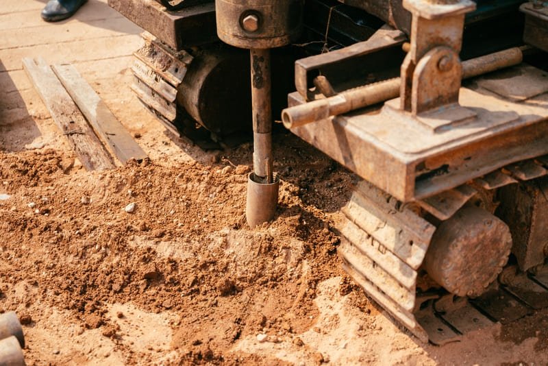 A DTH drill bit engaged in drilling hard rock with dust and debris flying around.
