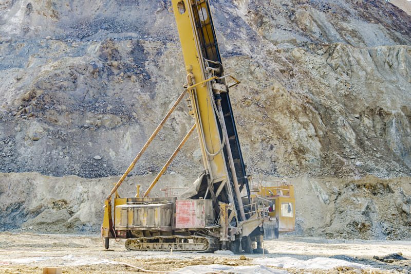 Down-The-Hole drill bit drilling into hard rock with dust flying