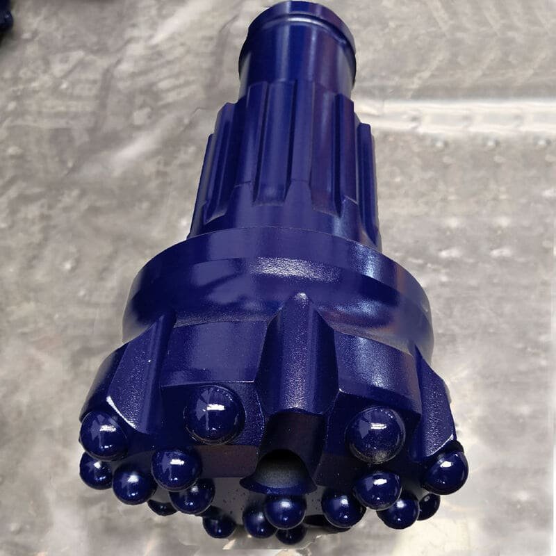 Close-up of various DTH drill bits on a wooden table