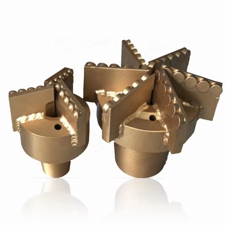 Close-up of PDC and tricone bits on a workbench, highlighting their structural differences
