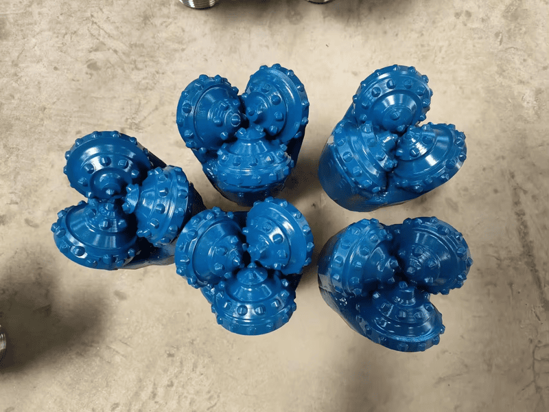 A tricone drill bit and a PDC bit placed side by side for comparison, highlighting their differences in design and application.