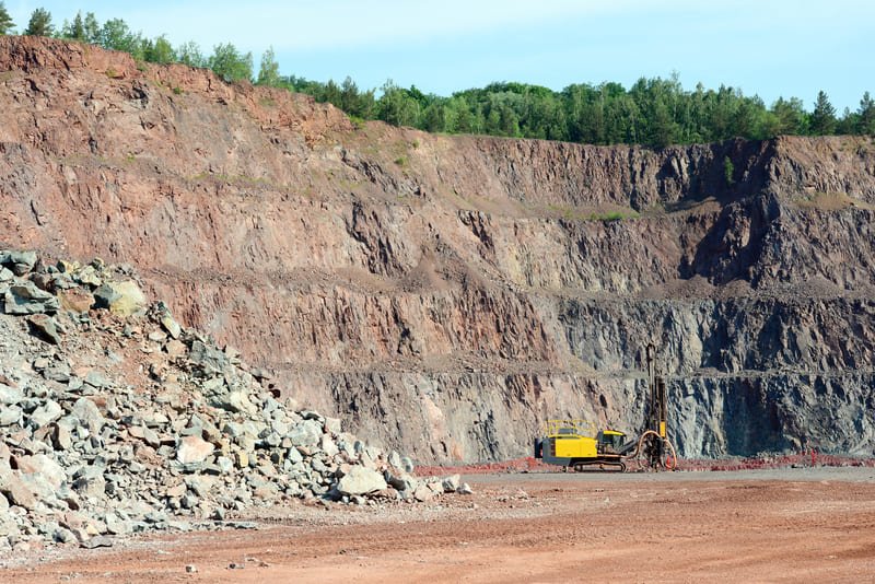 Close-up of a DTH drill bit and a PDC drill bit on a rocky surface