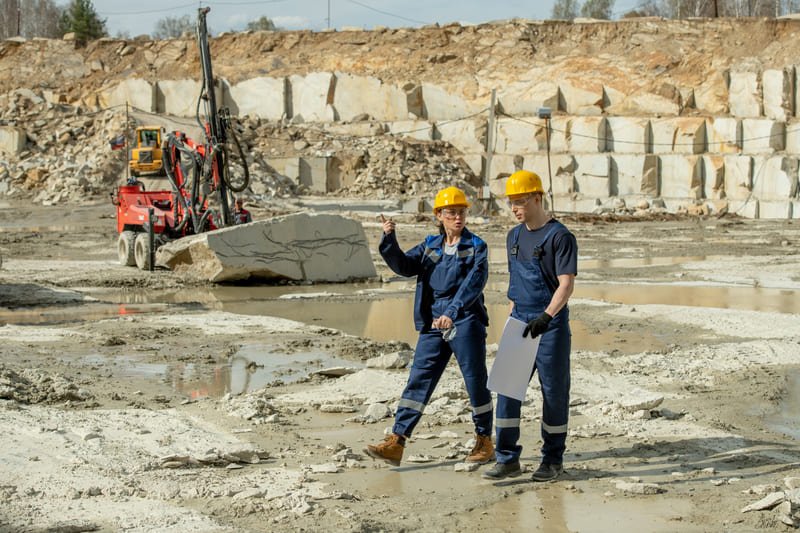 An array of drill bits and rock samples next to a drilling rig