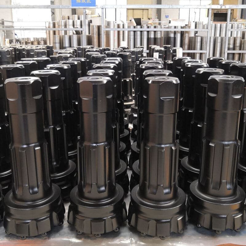 A collection of black DTH bits displayed together, showcasing various sizes and designs for drilling applications.