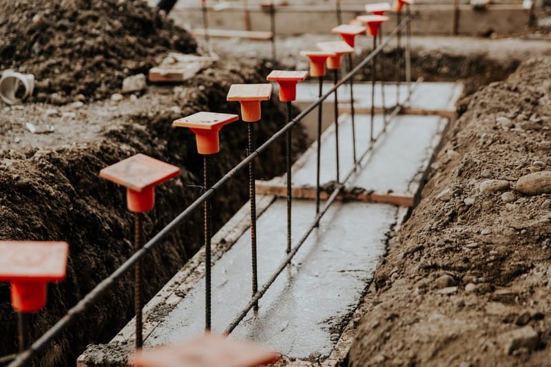 A construction worker securing an anchor in a concrete foundation, ensuring stability for a building structure.