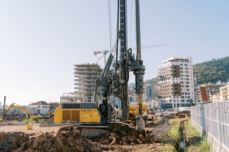 A DTH drilling site featuring heavy machinery and equipment, surrounded by a rugged landscape and clear blue sky.