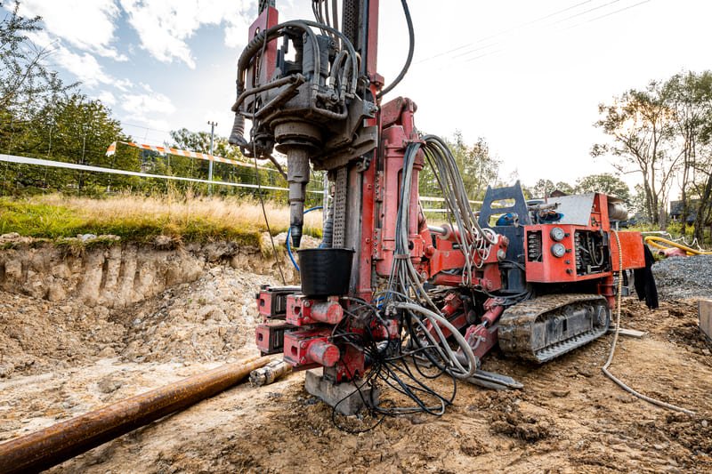 A DTH drilling site featuring heavy machinery and equipment, with workers engaged in drilling operations on rugged terrain.