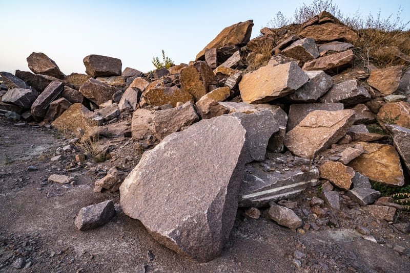 A close-up view of fractured rock, showcasing jagged edges and varying textures in earthy tones.