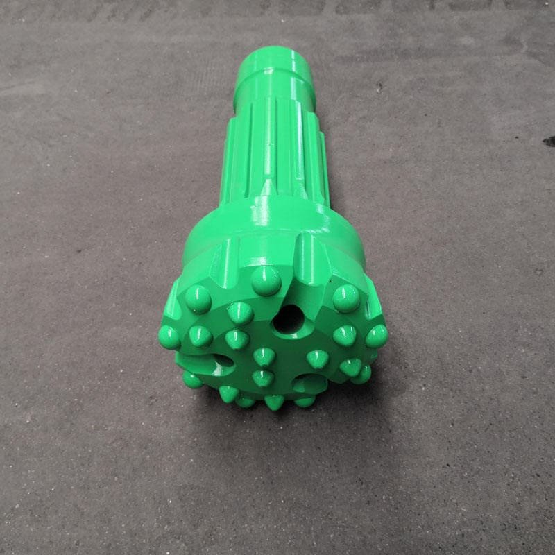 Detailed view of custom DTH drill bits on a wooden workbench