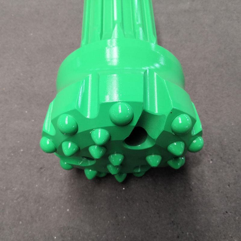 Close-up of a green DTH bit, showcasing its intricate design and sharp cutting edges for drilling applications.