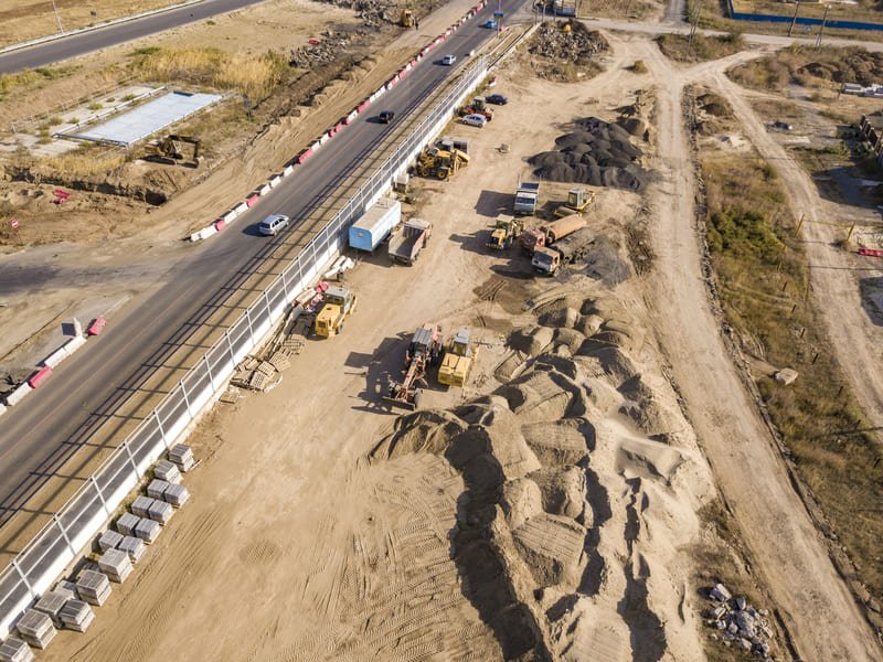 Ongoing highway construction with heavy machinery and workers, showcasing progress on road improvements and infrastructure development.