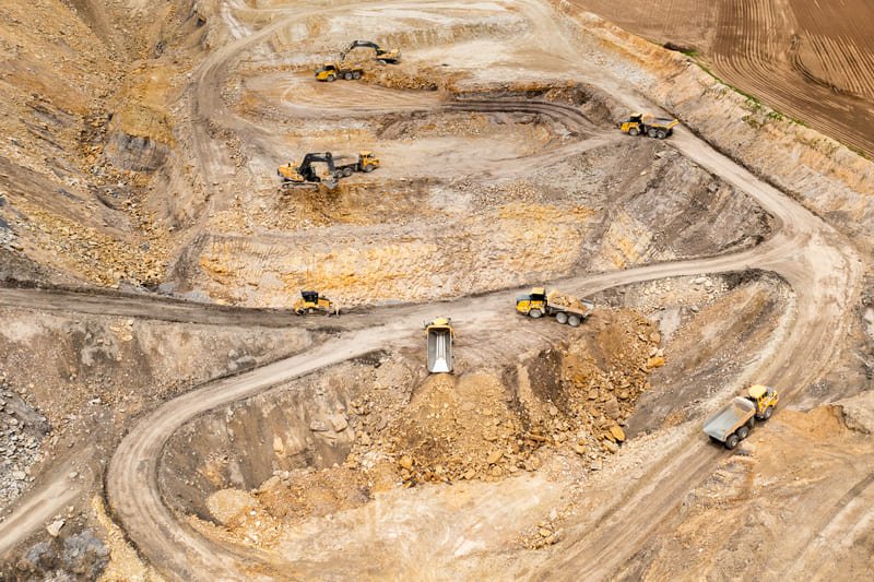 Aerial view of mining operations showcasing heavy machinery and excavation sites in a rugged landscape.