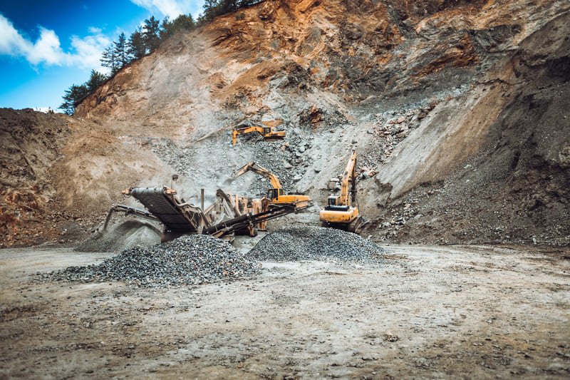 Aerial view of a mining site showcasing heavy machinery and excavated land surrounded by natural terrain.