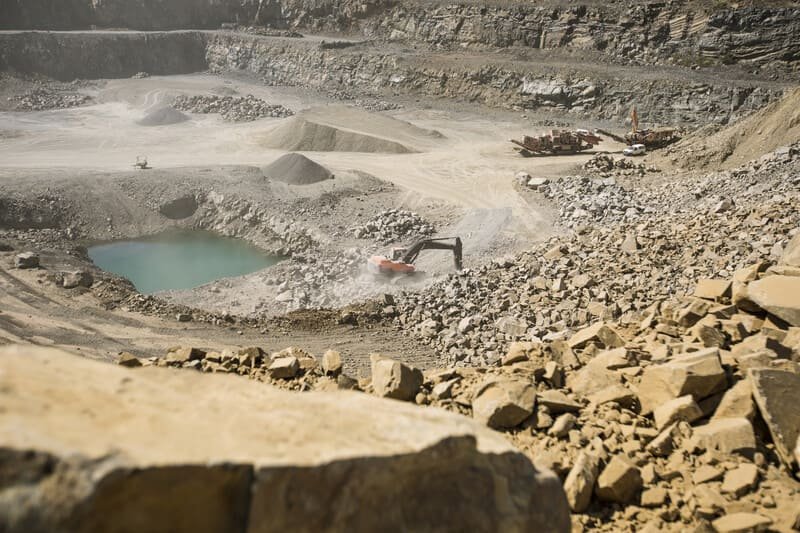 Aerial view of a mining site showcasing heavy machinery and excavated land surrounded by natural terrain.