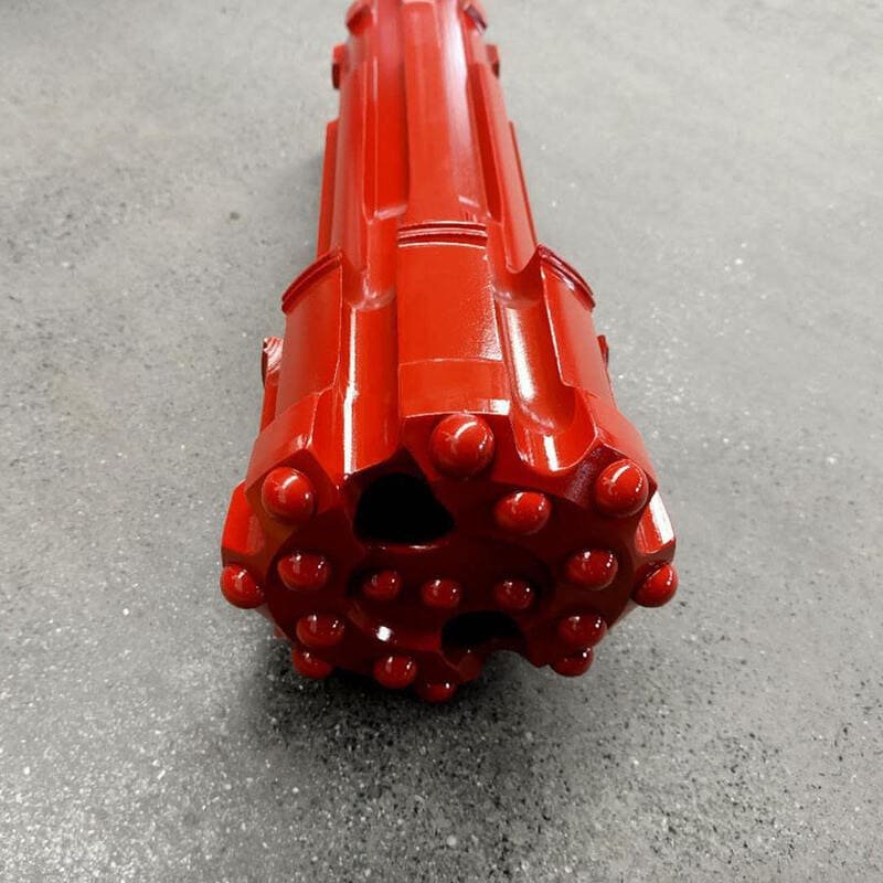 Close-up of a red DTH drill bit, showcasing its intricate design and sharp cutting edges for efficient drilling.
