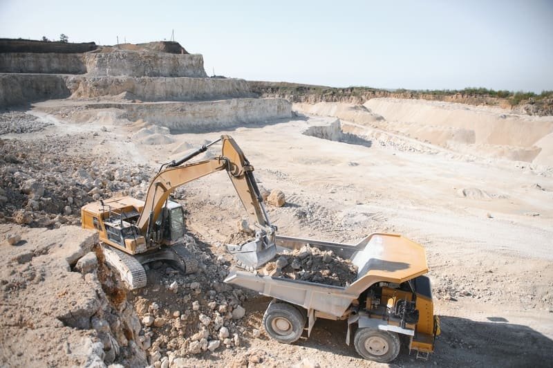 A detailed view of a quarrying site showcasing heavy machinery and rock extraction activities in a rugged landscape.