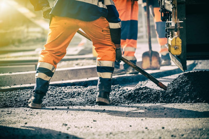 A construction crew working on a road, with machinery and barriers in place, ensuring safe and efficient road improvements.