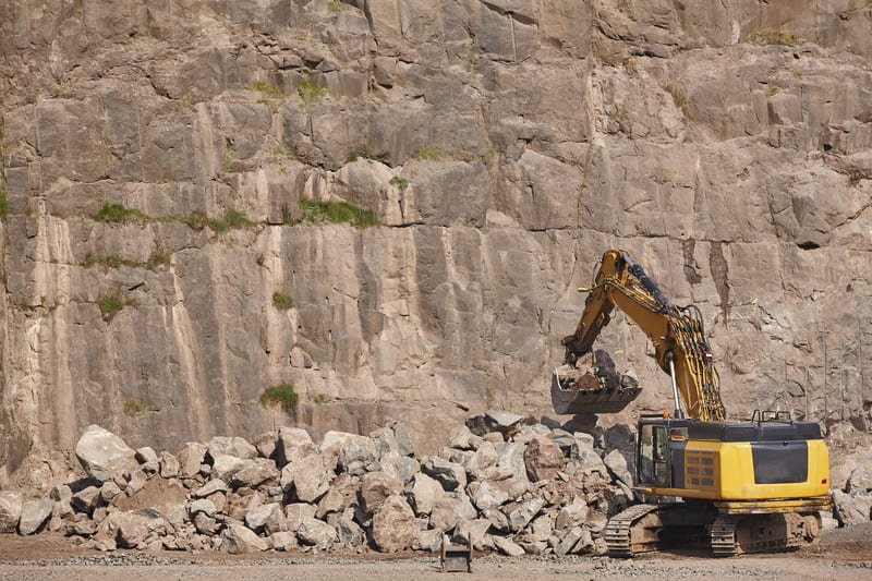 A vast stone quarry showcasing rugged terrain, large boulders, and machinery used for extracting stone materials.
