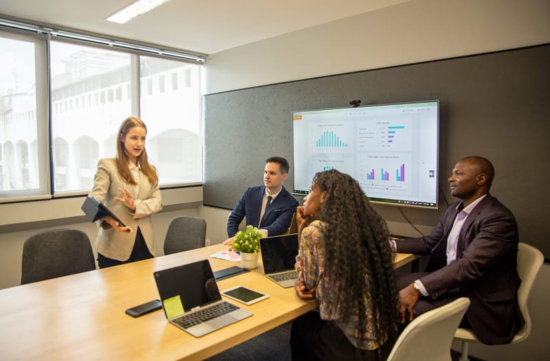 A group of professionals engaged in a business discussion around a conference table in a well-lit meeting room.