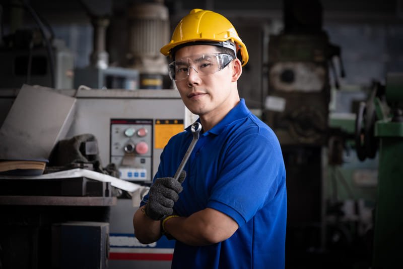 Close-up of a technician inspecting a metallic drill bit on a workbench