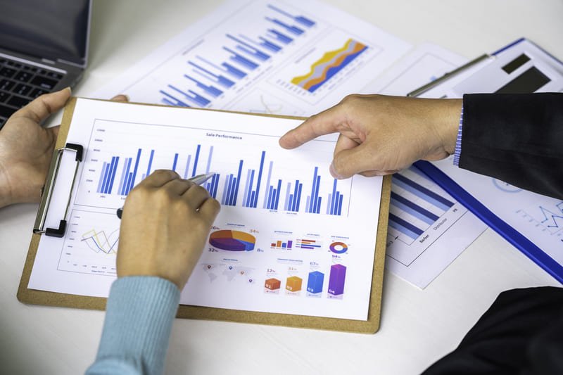 A professional conducting financial analysis, reviewing charts and data on a laptop in a modern office setting.