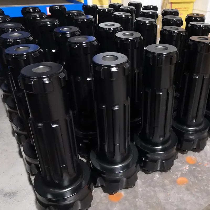 A collection of black DTH drill bits displayed together, showcasing their various sizes and designs for drilling applications.